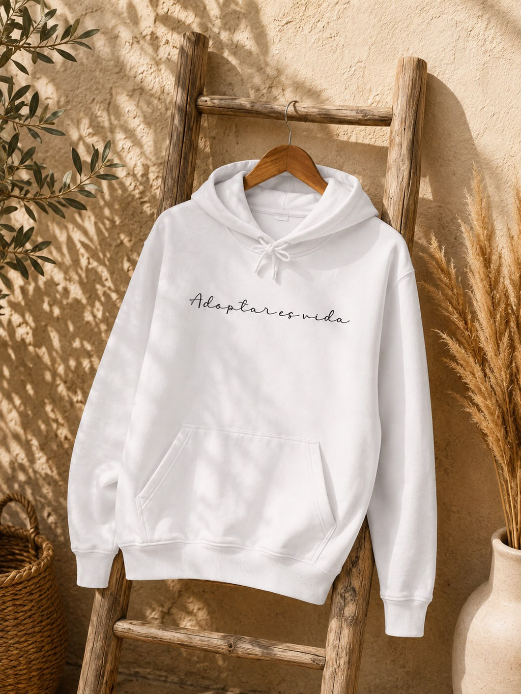 La sudadera blanca «Adoptar es vida» colgada de una escalera de madera